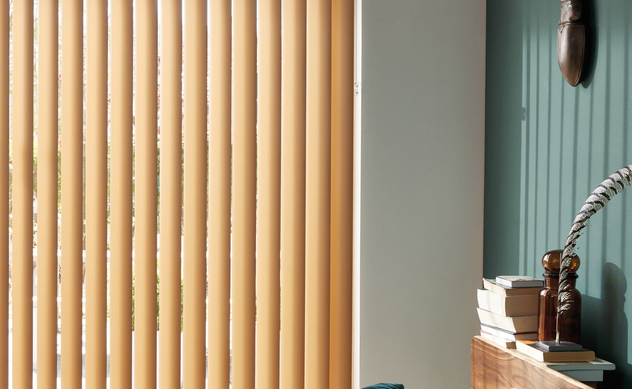 Ein Schlafzimmer mit einem Bett, bunten Kissen und einer großen Fensterjalousie in Orange. Eine Wand ist in einem sanften Grünton gestrichen.